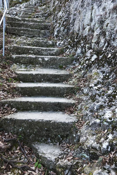 An old open outer stone staircase. Stone, cement steps of the old staircase with traces of weathering and destruction. An ancient stone staircase, ancient broken worn steps. Selective focus