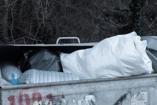 Full garbage cans with garbage. Construction white trash bags filled the container for household waste. The problem of recycling domestic waste