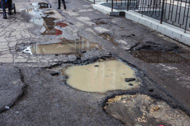 Çok kötü kalite yol çukurların ile. Asfalt, kötü asfalt delik. Çukur, güvensiz, delik yol. Ulaşım, yollar, imha hareketi tarafından araba konsepti riski. Kötü yollar kavramı