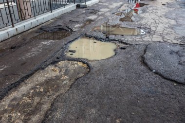 Çok kötü kalite yol çukurların ile. Asfalt, kötü asfalt delik. Çukur, güvensiz, delik yol. Ulaşım, yollar, imha hareketi tarafından araba konsepti riski. Kötü yollar kavramı