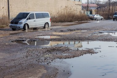 Odessa, Ukrayna 5 Mart 2019: Asfalt yol ile çukurların dondurma ve çözme döngüsü sırasında belgili tanımlık kış nedeniyle zarar görmüş. Arabalar su çukurlara kötü yol