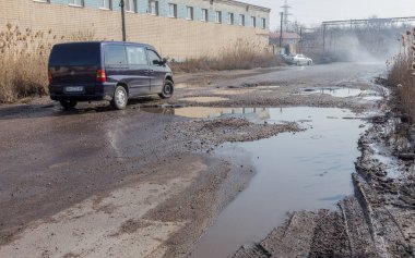 Odessa, Ukrayna 5 Mart 2019: Asfalt yol ile çukurların dondurma ve çözme döngüsü sırasında belgili tanımlık kış nedeniyle zarar görmüş. Arabalar su çukurlara kötü yol