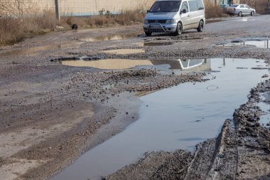 Odessa, Ukrayna 5 Mart 2019: Asfalt yol ile çukurların dondurma ve çözme döngüsü sırasında belgili tanımlık kış nedeniyle zarar görmüş. Arabalar su çukurlara kötü yol