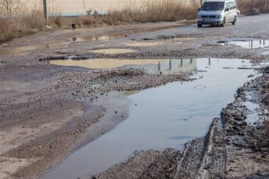 Odessa, Ukrayna 5 Mart 2019: Asfalt yol ile çukurların dondurma ve çözme döngüsü sırasında belgili tanımlık kış nedeniyle zarar görmüş. Arabalar su çukurlara kötü yol