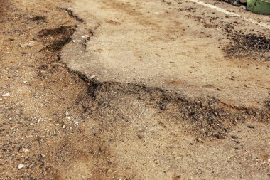 Büyük çatlaklar, cips, tabak. Kırık asfalt heyelan bir depremden sonra değiştirdi. Yolda tehlikeli derin çatlaklar. Yol kapalı. Deprem sonrası terk edilmiş yol yok asfalt üzerinde çatlaklar oluşan tablo