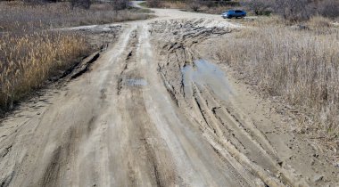 Devreden. Derin lastik paletler yolda ıslak kirli kum ile off-road kaplıdır. Kir lastik izleri. Motocross ve autosport geçilmez yolluk. Kum tekerlek izleri