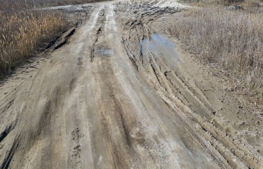 Devreden. Derin lastik paletler yolda ıslak kirli kum ile off-road kaplıdır. Kir lastik izleri. Motocross ve autosport geçilmez yolluk. Kum tekerlek izleri