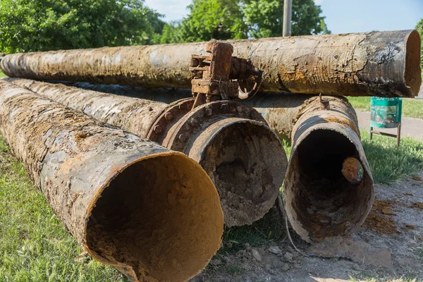 Fragments of old large water pipes. After many years of operation, corroded metal pipe destroyed. Rusty steel tube with holes metal corrosion. Selective focus.