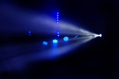 Sahne ışıkları. Karanlıkta birkaç projektör var. Gösteri sırasında sahnenin sahne ışıklarından gelen çok renkli ışık demetleri sahnenin dumanının içinde. Gece kulübü. Işıklar açık. Lazer gösterisi