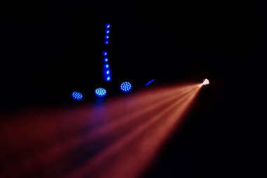 Sahne ışıkları. Karanlıkta birkaç projektör var. Gösteri sırasında sahnenin sahne ışıklarından gelen çok renkli ışık demetleri sahnenin dumanının içinde. Gece kulübü. Işıklar açık. Lazer gösterisi