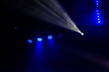 Sahne ışıkları. Karanlıkta birkaç projektör var. Gösteri sırasında sahnenin sahne ışıklarından gelen çok renkli ışık demetleri sahnenin dumanının içinde. Gece kulübü. Işıklar açık. Lazer gösterisi