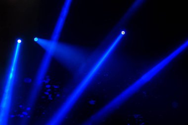 Sahne ışıkları. Karanlıkta birkaç projektör var. Gösteri sırasında sahnenin sahne ışıklarından gelen çok renkli ışık demetleri sahnenin dumanının içinde. Gece kulübü. Işıklar açık. Lazer gösterisi
