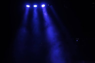 Sahne ışıkları. Karanlıkta birkaç projektör var. Gösteri sırasında sahnenin sahne ışıklarından gelen çok renkli ışık demetleri sahnenin dumanının içinde. Gece kulübü. Işıklar açık. Lazer gösterisi