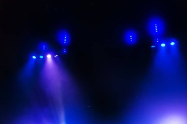 Sahne ışıkları. Karanlıkta birkaç projektör var. Gösteri sırasında sahnenin sahne ışıklarından gelen çok renkli ışık demetleri sahnenin dumanının içinde. Gece kulübü. Işıklar açık. Lazer gösterisi