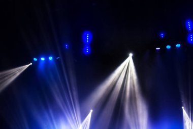 Sahne ışıkları. Karanlıkta birkaç projektör var. Gösteri sırasında sahnenin sahne ışıklarından gelen çok renkli ışık demetleri sahnenin dumanının içinde. Gece kulübü. Işıklar açık. Lazer gösterisi