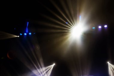 Sahne ışıkları. Karanlıkta birkaç projektör var. Gösteri sırasında sahnenin sahne ışıklarından gelen çok renkli ışık demetleri sahnenin dumanının içinde. Gece kulübü. Işıklar açık. Lazer gösterisi