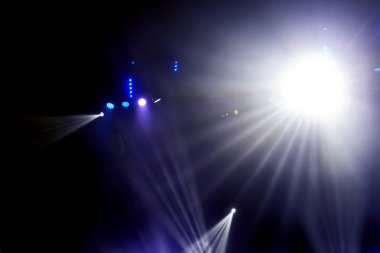 Sahne ışıkları. Karanlıkta birkaç projektör var. Gösteri sırasında sahnenin sahne ışıklarından gelen çok renkli ışık demetleri sahnenin dumanının içinde. Gece kulübü. Işıklar açık. Lazer gösterisi
