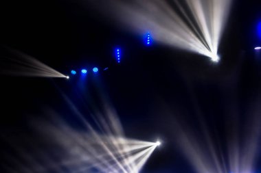 Sahne ışıkları. Karanlıkta birkaç projektör var. Gösteri sırasında sahnenin sahne ışıklarından gelen çok renkli ışık demetleri sahnenin dumanının içinde. Gece kulübü. Işıklar açık. Lazer gösterisi