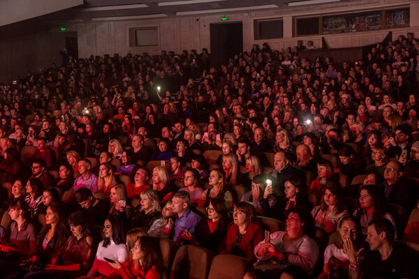 Odessa, Ukraine - April 12, 2019: Crowd of spectators at rock concert ALEKSEEV during music show. Crowds of happy people enjoy rock concert, raise their hands and clap their hands, audience on podiu