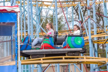 Odessa, Ukrayna - 6 Mayıs 2019: Ziyaretçiler bir lunaparkta yol kaydıraklarına biniyor. Heyecan verici bir lunapark treninde genç arkadaşlar. Gençler lunaparkta eğleniyor. Lunapark treninde korkunç eğlence