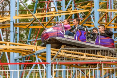 Odessa, Ukrayna - 6 Mayıs 2019: Ziyaretçiler bir lunaparkta yol kaydıraklarına biniyor. Heyecan verici bir lunapark treninde genç arkadaşlar. Gençler lunaparkta eğleniyor. Lunapark treninde korkunç eğlence