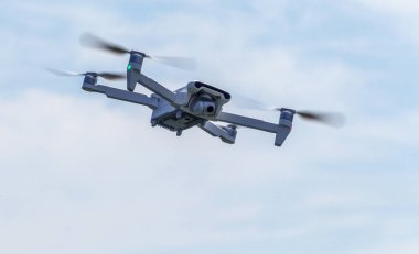 Profesyonel filme drone mavi bir gökyüzüne karşı düşük irtifada havada uçar. Drone fotoğraf yapar. Modern yeni teknoloji. Metin için yer ile hazır arka plan