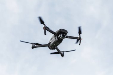 Profesyonel filme drone mavi bir gökyüzüne karşı düşük irtifada havada uçar. Drone fotoğraf yapar. Modern yeni teknoloji. Metin için yer ile hazır arka plan