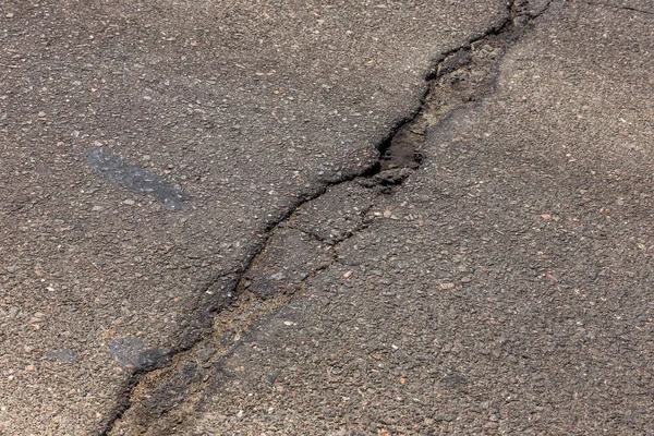 Estrada danificada, rachaduras de asfalto. Asfalto com buracos e asfalto — Fotografia de Stock