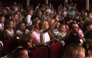 Odessa, Ukrayna - Circa 2019: seçici odak. Popüler çocuk oyunu sırasında tiyatroseyirci çocuklar. Çocuk Lokumu seyircisi. Konser seyircisi hareket halinde. Tiyatroda çocuk seyircisi