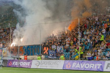 Odessa, Ukrayna -Temmuz28,2019: Fanatik taraftarlar ebedi rakipleri oyun sırasında standında. Raflarda hayranları mutlu, ateş ve bayrak sallayarak parlıyor. Stadyumda ateşli bir gösteri. Holigan ışık ateşli flaş Fan