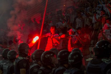 Odessa, Ukrayna -Temmuz28,2019: Fanatik taraftarlar ebedi rakipleri oyun sırasında standında. Raflarda hayranları mutlu, ateş ve bayrak sallayarak parlıyor. Stadyumda ateşli bir gösteri. Holigan ışık ateşli flaş Fan