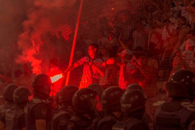 Odessa, Ukrayna -Temmuz28,2019: Fanatik taraftarlar ebedi rakipleri oyun sırasında standında. Raflarda hayranları mutlu, ateş ve bayrak sallayarak parlıyor. Stadyumda ateşli bir gösteri. Holigan ışık ateşli flaş Fan