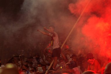 Odessa, Ukrayna -Temmuz28,2019: Fanatik taraftarlar ebedi rakipleri oyun sırasında standında. Raflarda hayranları mutlu, ateş ve bayrak sallayarak parlıyor. Stadyumda ateşli bir gösteri. Holigan ışık ateşli flaş Fan