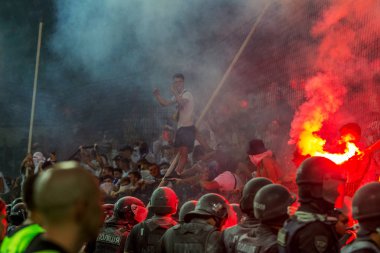 Odessa, Ukrayna -Temmuz28,2019: Fanatik taraftarlar ebedi rakipleri oyun sırasında standında. Raflarda hayranları mutlu, ateş ve bayrak sallayarak parlıyor. Stadyumda ateşli bir gösteri. Holigan ışık ateşli flaş Fan