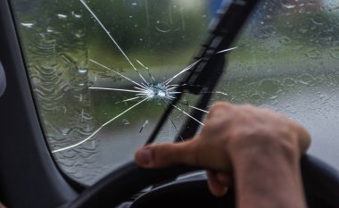 Bir arabanın kırık ön camı. Radyal bir ağ, tripleks ön camda çatlaklar. Kırık araba ön cam, yolda gelen taş izleri veya araba cam kurşun izi ile hasarlı cam