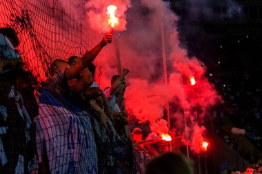 Odessa, Ukrayna -Temmuz28,2019: Fanatik taraftarlar ebedi rakipleri oyun sırasında standında. Raflarda hayranları mutlu, ateş ve bayrak sallayarak parlıyor. Stadyumda ateşli bir gösteri. Holigan ışık ateşli flaş Fan