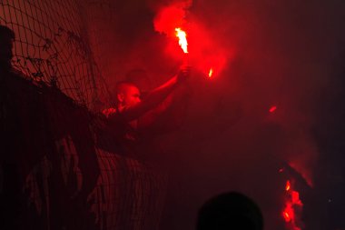 Odessa, Ukrayna -Temmuz28,2019: Fanatik taraftarlar ebedi rakipleri oyun sırasında standında. Raflarda hayranları mutlu, ateş ve bayrak sallayarak parlıyor. Stadyumda ateşli bir gösteri. Holigan ışık ateşli flaş Fan