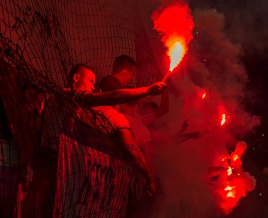 Odessa, Ukrayna -Temmuz28,2019: Fanatik taraftarlar ebedi rakipleri oyun sırasında standında. Raflarda hayranları mutlu, ateş ve bayrak sallayarak parlıyor. Stadyumda ateşli bir gösteri. Holigan ışık ateşli flaş Fan