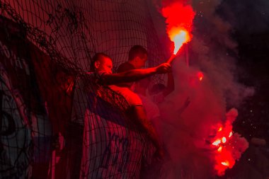 Odessa, Ukrayna -Temmuz28,2019: Fanatik taraftarlar ebedi rakipleri oyun sırasında standında. Raflarda hayranları mutlu, ateş ve bayrak sallayarak parlıyor. Stadyumda ateşli bir gösteri. Holigan ışık ateşli flaş Fan