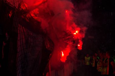 Odessa, Ukrayna -Temmuz28,2019: Fanatik taraftarlar ebedi rakipleri oyun sırasında standında. Raflarda hayranları mutlu, ateş ve bayrak sallayarak parlıyor. Stadyumda ateşli bir gösteri. Holigan ışık ateşli flaş Fan
