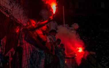 Odessa, Ukrayna -Temmuz28,2019: Fanatik taraftarlar ebedi rakipleri oyun sırasında standında. Raflarda hayranları mutlu, ateş ve bayrak sallayarak parlıyor. Stadyumda ateşli bir gösteri. Holigan ışık ateşli flaş Fan