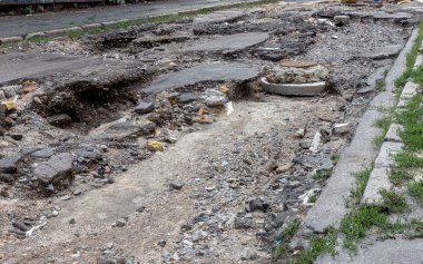 Büyük çatlaklar, cipsler. Kırık asfalt sel sonrası heyelan değiştirdi. Su yla yok edilmiş bir yol. Yeraltı suyu sifonu. Doğadan yolların tahrip kavramı. Selin sonuçları. Kırık sokak