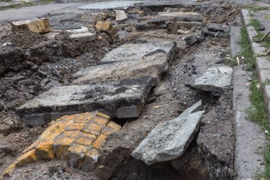 Büyük çatlaklar, cipsler. Kırık asfalt sel sonrası heyelan değiştirdi. Su yla yok edilmiş bir yol. Yeraltı suyu sifonu. Doğadan yolların tahrip kavramı. Selin sonuçları. Kırık sokak