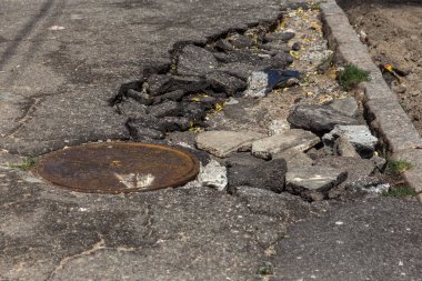 Büyük çatlaklar, cipsler. Kırık asfalt sel sonrası heyelan değiştirdi. Su yla yok edilmiş bir yol. Yeraltı suyu sifonu. Doğadan yolların tahrip kavramı. Selin sonuçları. Kırık sokak