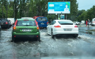 Odessa, Ukrayna -9 Ağustos 2019: sağanak yağışların neden olduğu sel felaketi sırasında su lar altında kalan yolda araba sürmek. Arabalar su üzerinde yüzüyor, sokakları su basayor. Arabaya sıçrat. Büyük bir su birikintisi ile sular altında şehir yolu