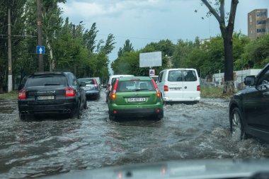 Odessa, Ukrayna -9 Ağustos 2019: sağanak yağışların neden olduğu sel felaketi sırasında su lar altında kalan yolda araba sürmek. Arabalar su üzerinde yüzüyor, sokakları su basayor. Arabaya sıçrat. Büyük bir su birikintisi ile sular altında şehir yolu