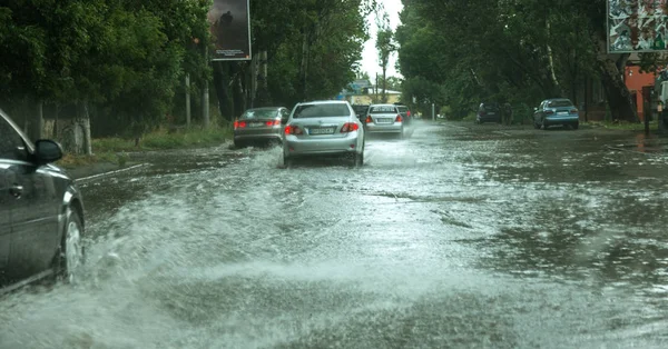 Odessa, Ukrayna -9 Ağustos 2019: sağanak yağışların neden olduğu sel felaketi sırasında su lar altında kalan yolda araba sürmek. Arabalar su üzerinde yüzüyor, sokakları su basayor. Arabaya sıçrat. Büyük bir su birikintisi ile sular altında şehir yolu