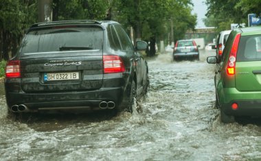 Odessa, Ukrayna -9 Ağustos 2019: sağanak yağışların neden olduğu sel felaketi sırasında su lar altında kalan yolda araba sürmek. Arabalar su üzerinde yüzüyor, sokakları su basayor. Arabaya sıçrat. Büyük bir su birikintisi ile sular altında şehir yolu