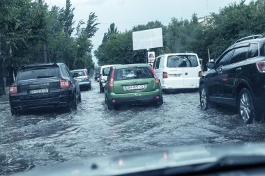 Odessa, Ukrayna -9 Ağustos 2019: sağanak yağışların neden olduğu sel felaketi sırasında su lar altında kalan yolda araba sürmek. Arabalar su üzerinde yüzüyor, sokakları su basayor. Arabaya sıçrat. Büyük bir su birikintisi ile sular altında şehir yolu