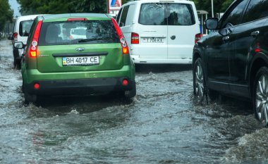 Odessa, Ukrayna -9 Ağustos 2019: sağanak yağışların neden olduğu sel felaketi sırasında su lar altında kalan yolda araba sürmek. Arabalar su üzerinde yüzüyor, sokakları su basayor. Arabaya sıçrat. Büyük bir su birikintisi ile sular altında şehir yolu
